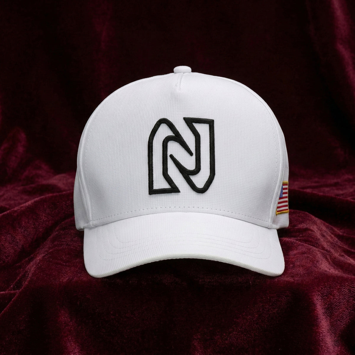 White cap with a black logo on a dark red fabric background