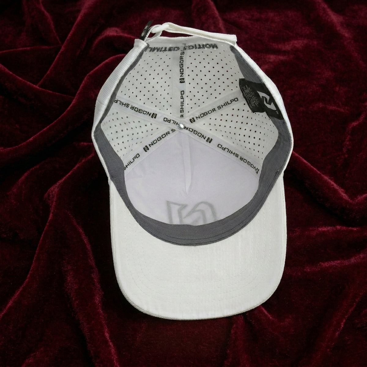 White cap with gray brim on a red textured background