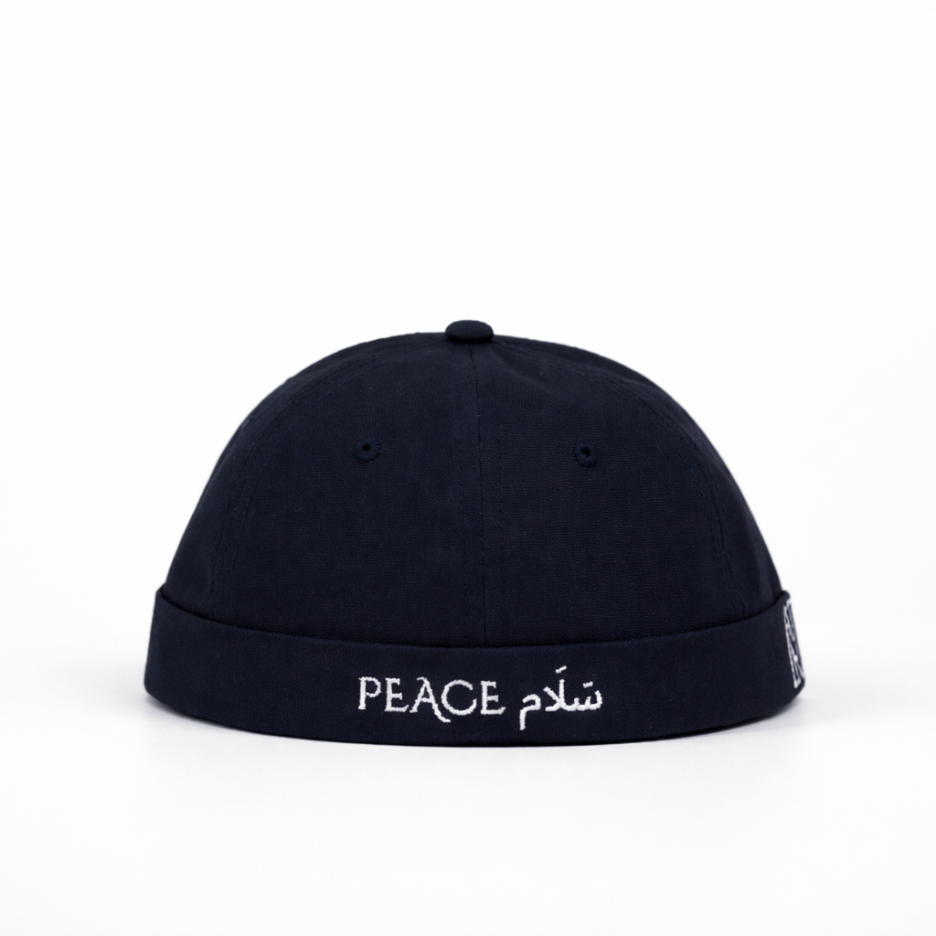 Black cap with 'PEACE' and Arabic text on a white background