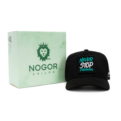 Black cap with 'Never Stop Dreaming' text and green box labeled 'NOGOR SHILPO' on a white background